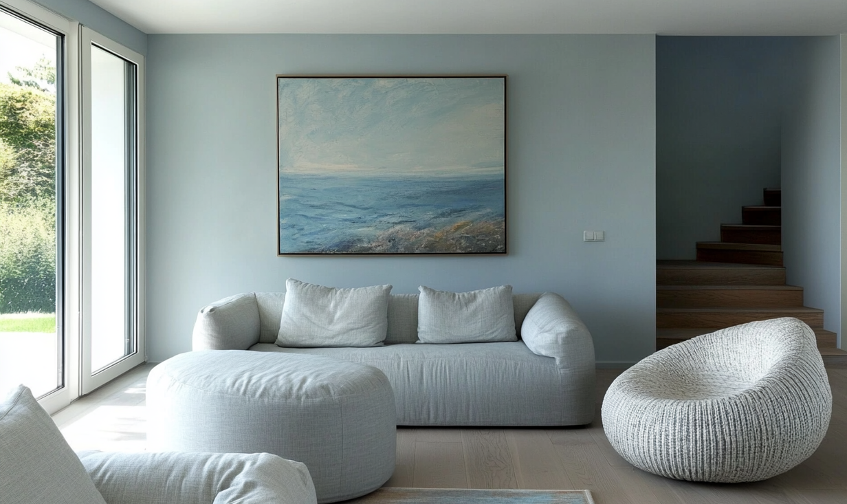 Salon minimaliste peint en Givre Bleu Clair, mobilier aux lignes arrondies en lin et fauteuil tissé, ambiance zen et lumineuse